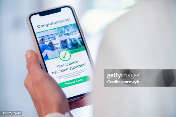 frau hält ein mobiltelefon mit kreditantrag genehmigung. - bewerbungsformular stock-fotos und bilder