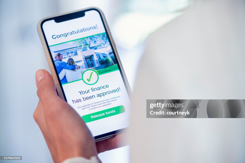 Woman holding a mobile phone with loan application approval.