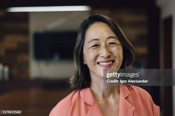 portret van een lachende oosterse volwassen vrouw - early retirement stockfoto's en -beelden