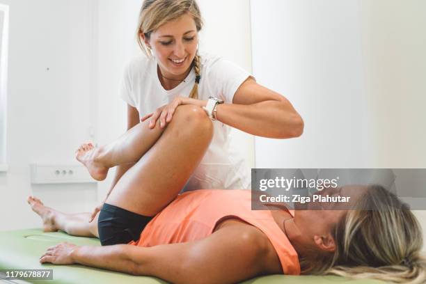 physio bending the patient leg, pressing the knee on her core - osteopath stock pictures, royalty-free photos & images