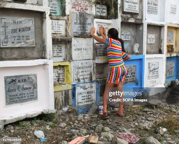 Girls at the tombstone of their deceased kin. Filipinos flock to cemeteries around the country to visit departed relatives and loved ones to remember...