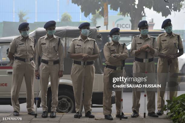 Indian police personnel wearing face masks stand guard amidts heavy smog conditions near a demonstration against air pollution in New Delhi on...