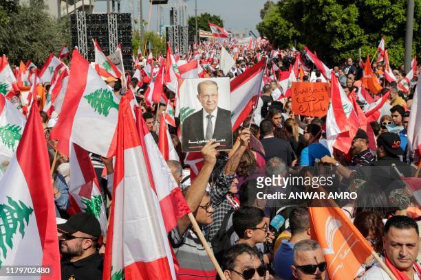 Supporter of Lebanese President Michel Aoun holds his picture during a counter-protest near the presidential palace in Baabda on November 3, 2019....
