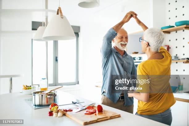 volwassen paar plezier tijdens het koken lunch. - healthy older couple stockfoto's en -beelden