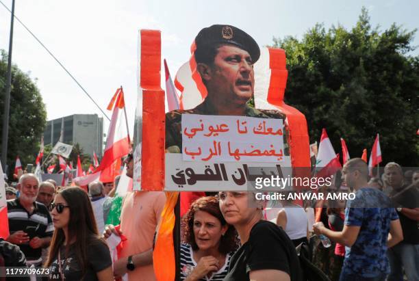 Supporters of Lebanese President Michel Aoun holds a placard reading "With you till death" during a counter-protest near the presidential palace in...