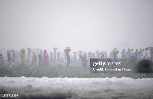 Devotees perform rituals in the polluted waters of Yamuna river at Kalindi Kunj on the occasion of Chhath Puja, on November 3, 2019 in Noida, India....