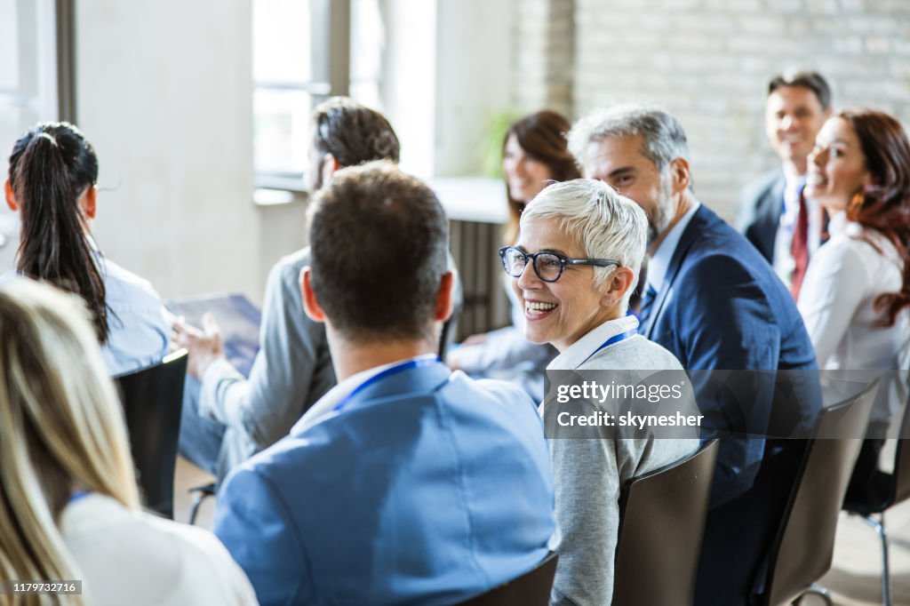 Happy senior businesswoman talking to her colleagues on seminar in the office.