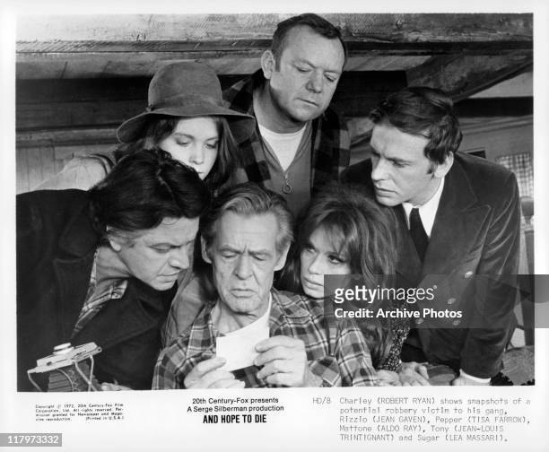 Robert Ryan showing a photograph to Jean Gaven, Tisa Farrow, Aldo Ray, Jean-Louis Trintignant and Lea Massari in a scene from the film 'And Hope to...