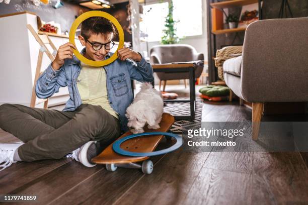 playful teenage boy and his pet at apartment - children circle floor stock pictures, royalty-free photos & images