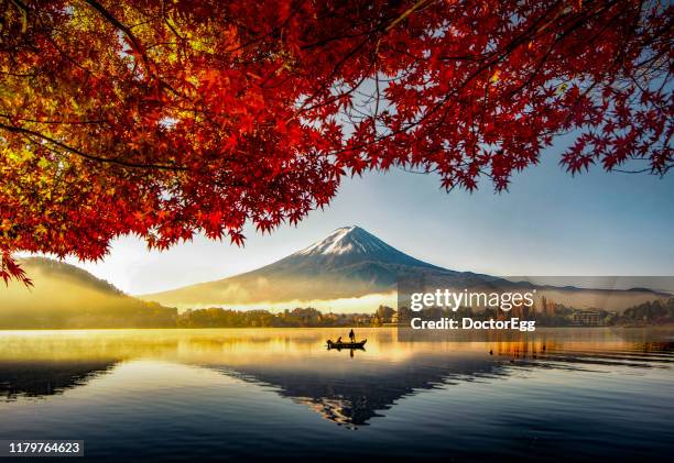 fuji mountain and fisherman boat with morning mist in autumn, kawaguchiko lake, japan - november stock-fotos und bilder