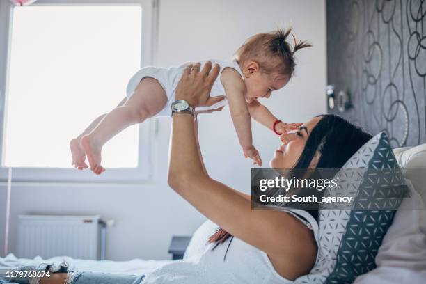 young mom holding a baby in arms - holding aloft stock pictures, royalty-free photos & images