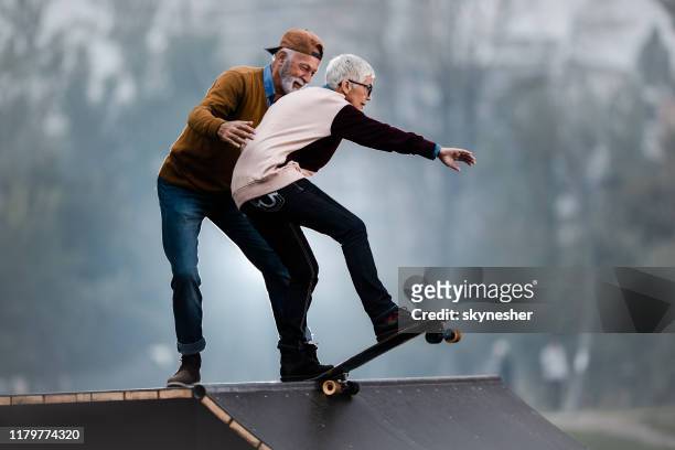 jong bij hart senior paar plezier hebben in skatepark. - mature couple winter outdoors stockfoto's en -beelden