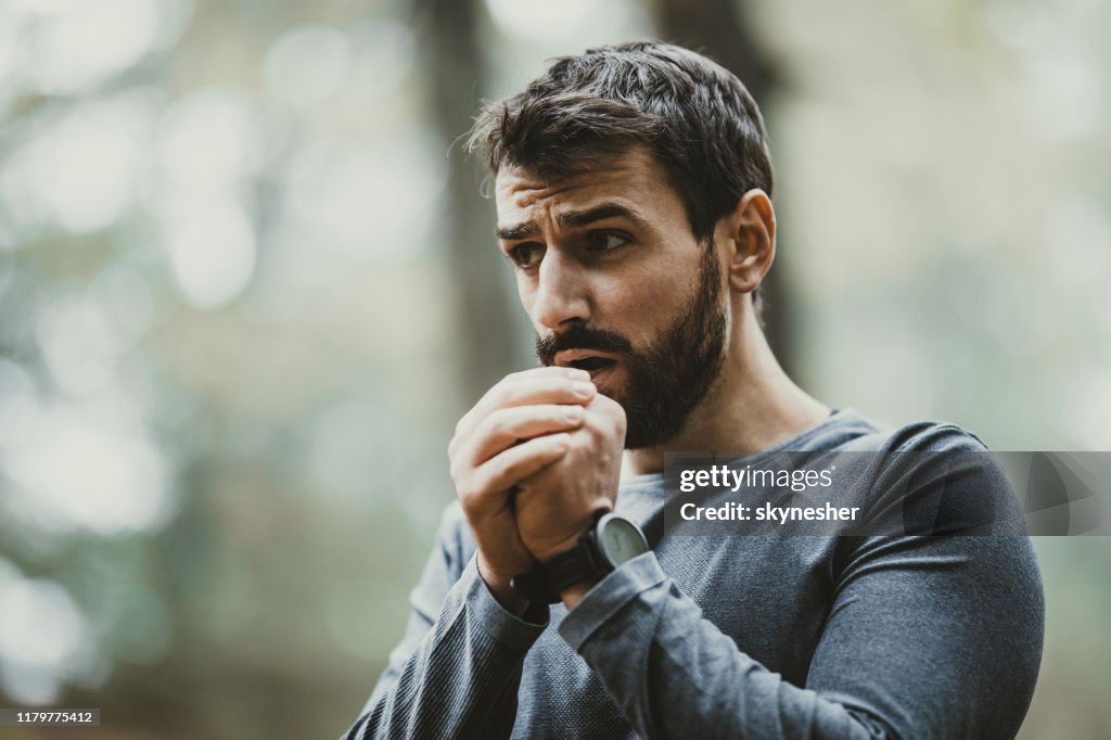 Young man warming his hands during cold in nature.