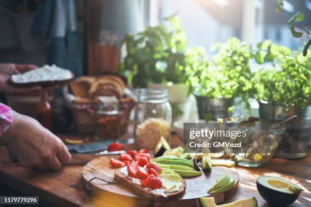 zubereitung von avocado sandwich mit braunbrot, frischkäse und erdbeeren - schmierkäse stock-fotos und bilder