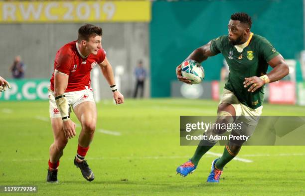 Siya Kolisi of South Africa runs with the ball from Andrew Coe of Canada during the Rugby World Cup 2019 Group B game between South Africa and Canada...