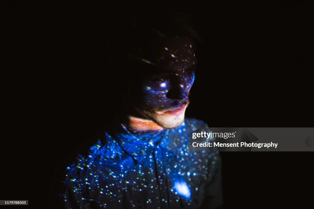 Man covered by colorful abstract patterns projected onto his face