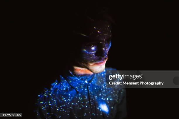 man covered by colorful abstract patterns projected onto his face - projector photos et images de collection