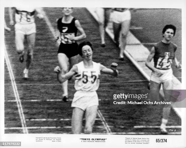 Ann Packer crosses the finish line in a scene from the film 'Tokyo Olympiad', 1965.