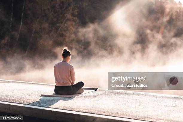 junge frau, die am frühen morgen yoga trainiert - meditation stock-fotos und bilder