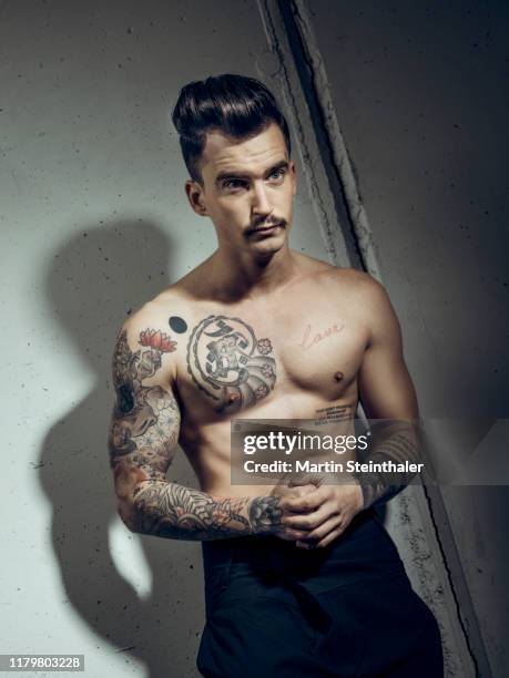 junger mann mit tattoos posiert oberkörperfrei vor betonwand - betonwand stock pictures, royalty-free photos & images