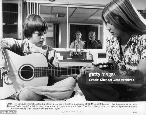 Michael Bolland plays guitar with the help of Teresa Laughlin in a scene from the film 'The Trial of Billy Jack', 1974.