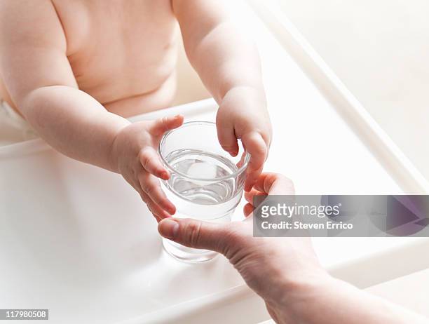 mother handing baby a glass of water - familly glasses stockfoto's en -beelden