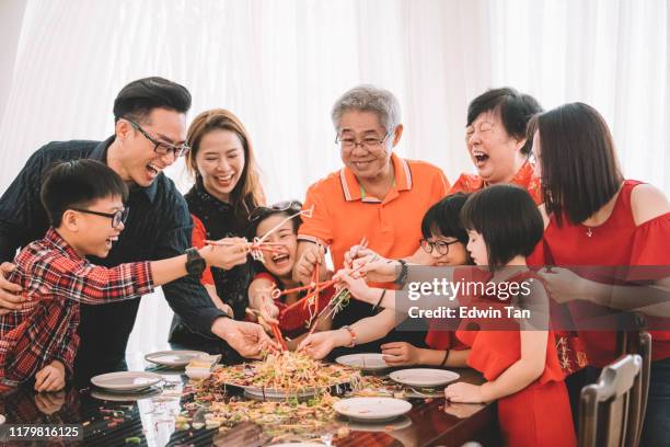 an asian chinese family celebrating chinese new year's eve with traditional food lou sang (raw fish dishes) during reunion dinner - chinese family dinner stock pictures, royalty-free photos & images