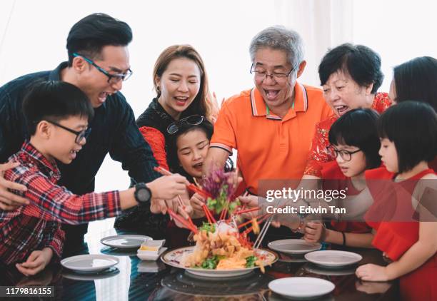 una familia china asiática celebrando la víspera de año nuevo chino con comida tradicional que lou cantó (platos de pescado crudo) durante la cena de reunión - reencuentro fotografías e imágenes de stock