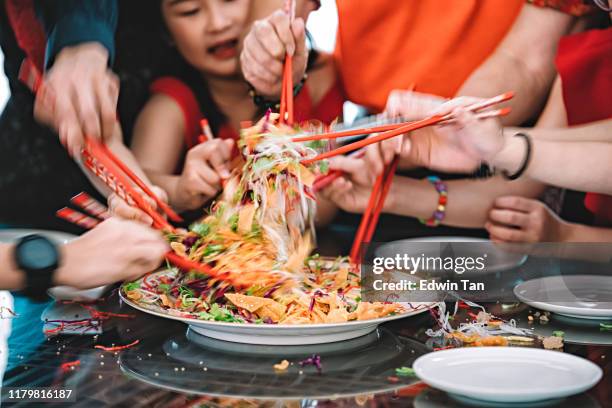 eine asiatische chinesische familie feiert chinesischen silvester mit traditionellen speisen lou sang (rohe fischgerichte) beim wiedersehen abendessen - chinese new year food stock-fotos und bilder