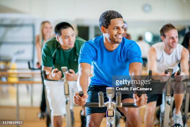 exercising class stock photo - indoor cycling stock pictures, royalty-free photos & images