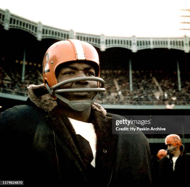 Jim Brown of the Cleveland Browns stands on the sidelines bundled up during an NFL game against the New York Giants on December 12, 1964 at Yankee...