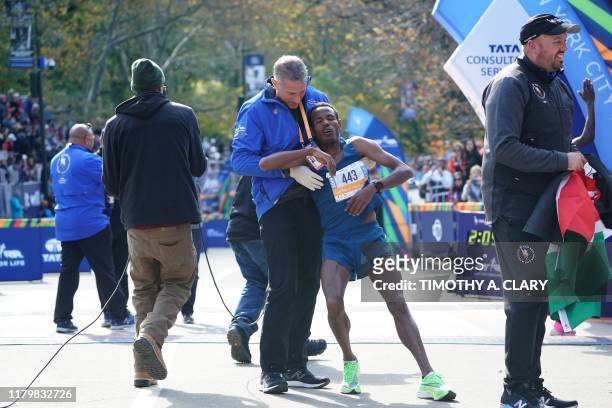 Third place finisher Girma Bekele Gebre of Ethiopia is helped during the Professional Men's Finish during the 2019 TCS New York City Marathon in New...