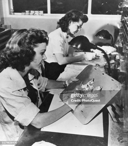 Two unidentified artists paint animation cels in Disney Studios' inking and painting department, Burbank, California, 1943.