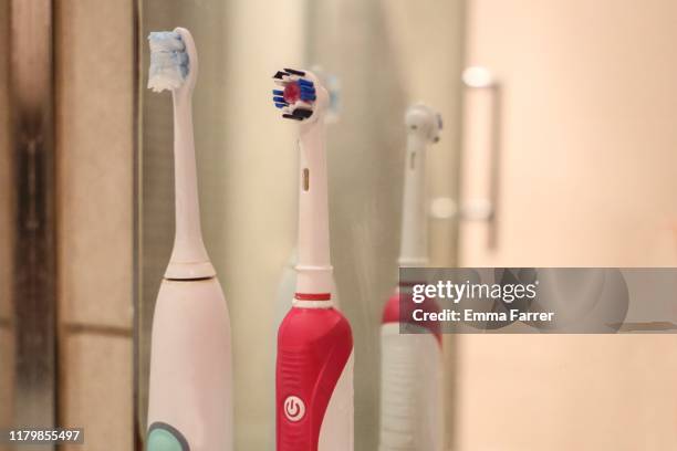 two electric toothbrushes in a bathroom - elektrische zahnbürste stock-fotos und bilder