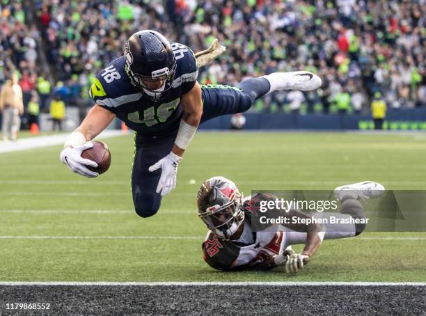 Tight end Jacob Hollister of the Seattle Seahawks dives over defensive back Sean Murphy-Bunting of the Tampa Bay Buccaneers to score a touchdown...