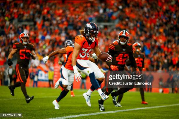 Running back Phillip Lindsay of the Denver Broncos scores a touchdown as safety Morgan Burnett of the Cleveland Browns looks on during the third...