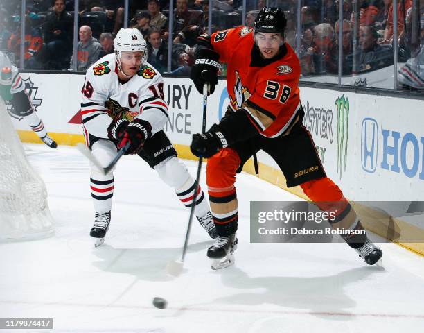 Derek Grant of the Anaheim Ducks passes the puck with pressure from Jonathan Toews of the Chicago Blackhawks during the first period of the game at...