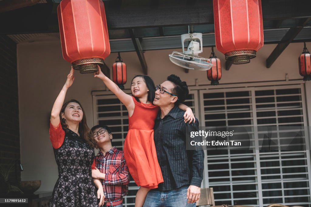 Una familia china asiática en malaysia arreglar sus linternas rojas para la preparación de año nuevo chino en frente de su casa