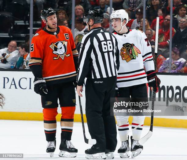 Ryan Getzlaf of the Anaheim Ducks and Kirby Dach of the Chicago Blackhawks talk with linesman Scott Driscoll during the third period of the game at...