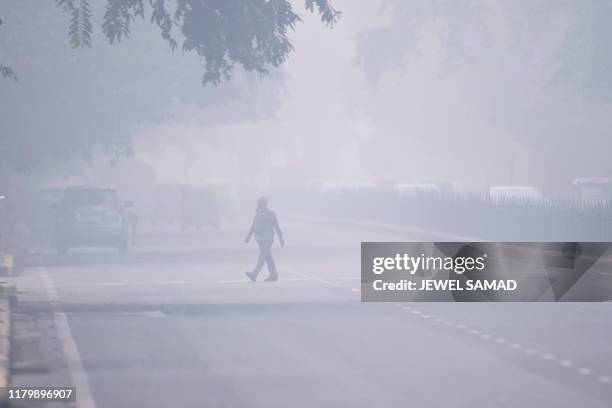 Man crosses a street in smoggy conditions in New Delhi on November 4, 2019. Millions of people in India's capital started the week on November 4...