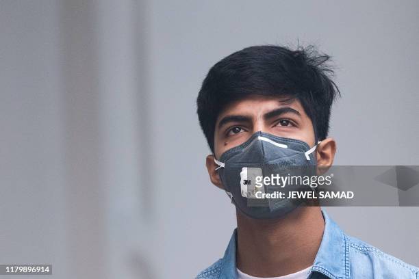 Youth wearing a protective face mask walks along a street in smoggy conditions in New Delhi on November 4, 2019. - Millions of people in India's...