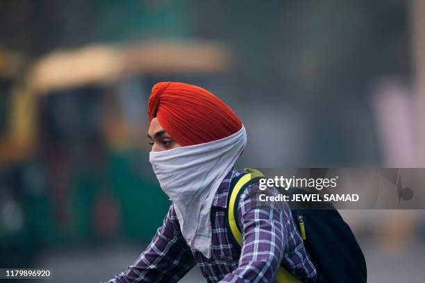 Motorist covering up his face rides along a street in smoggy conditions in New Delhi on November 4, 2019. - Millions of people in India's capital...