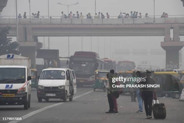 People make their way on a street in smoggy conditions in New Delhi on November 4, 2019. - Millions of people in India's capital started the week on...