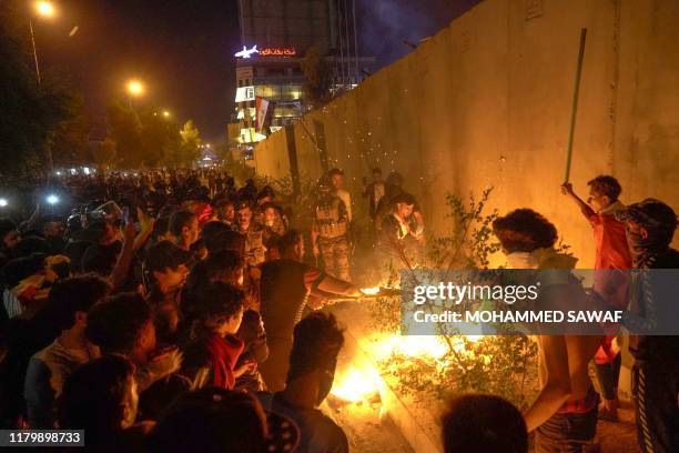 Iraqi demonstrators set tires ablaze behind the walls protecting the Iranian consulate in the Shiite Muslim shrine city of Karbala, south of Iraq's...