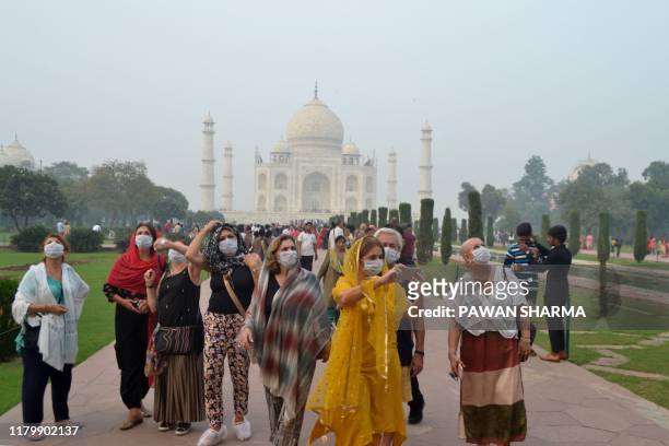 Foreign tourists wearing face masks visit the Taj Mahal under heavy smog conditions, in Agra on November 4, 2019. As smog levels exceeded those of...