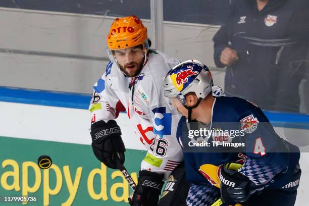 Dominik Uher of Fischtown Pinguins Bremerhaven and Blake Parlett of EHC Red Bull Muenchen battle for the puck during the DEL match between EHC Red...