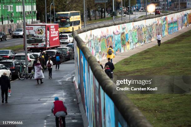 Tourists walk at a former section of the Berlin Wall called the East Side Gallery on the first day of events celebrating the 30th anniversary of the...