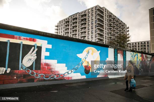 Tourists stand at a former section of the Berlin Wall called the East Side Gallery on the first day of events celebrating the 30th anniversary of the...