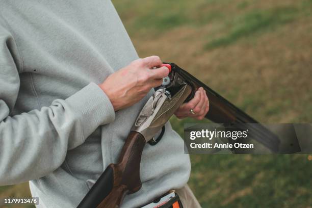 man loading shotgun shells into a gun - jachtgeweer stockfoto's en -beelden