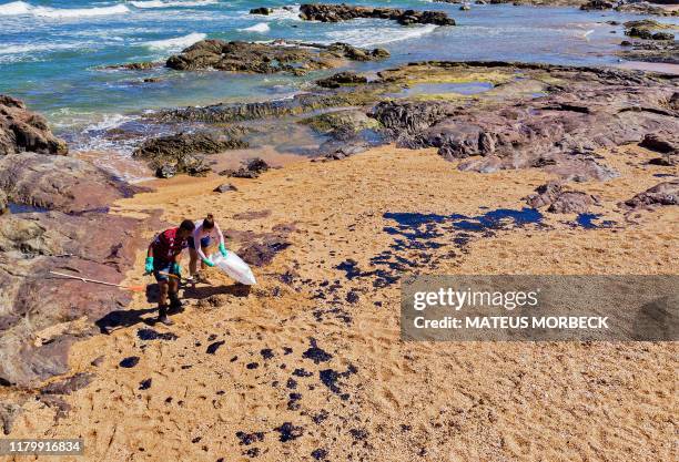 Volunteers remove crude oil spilled at Praia de Busca Vida beach in Camacari, Bahia state, Brazil, during a clean up operation on November 3, 2019. -...